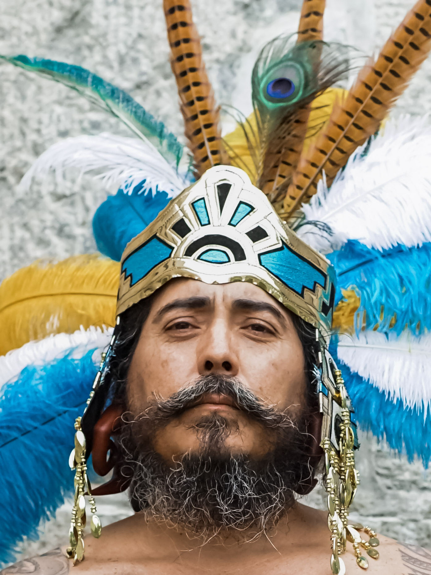 Rev Chief Mundo Santillan in feathered ceremonial headdress, direct gaze.